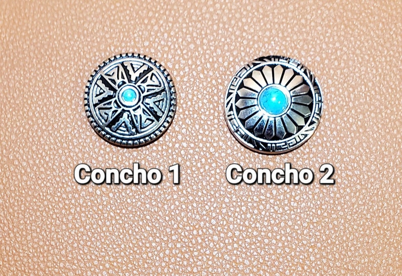 May include: Two silver-toned conchos with turquoise-colored centers. The conchos are round with detailed geometric designs. The text "Concho 1" and "Concho 2" are below each concho.