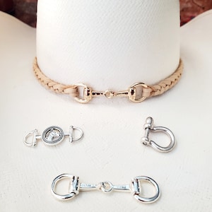 May include: A set of three gold and silver horse bit style clasps. The clasps are on a white surface. The clasps are used for making jewelry or other crafts.