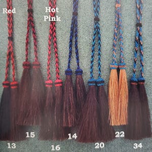 May include: Close-up of six different coloured braided leather tassels with a black and white braided cord. The tassels are labelled with numbers 13, 15, 16, 14, 20, 22, and 34. The colours of the tassels are red, hot pink, blue, and brown.
