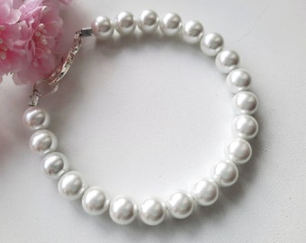 May include: A white pearl bracelet with a silver clasp. The bracelet is made of round pearls and is approximately 18 inches long.