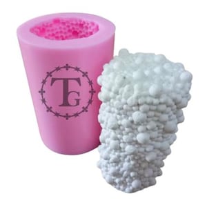 May include: Pink silicone mold with a textured surface. The mold is shaped like a cylinder and has a circular opening at the top. The mold has a logo with the letters "TG" inside a circle.
