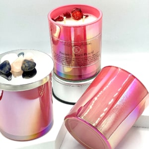 May include: Three pink iridescent glass candle jars with a white wax base and dried flowers on top. The candle jars have a silver lid and are labeled "Protect Your Peace!"