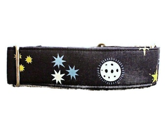 May include: A black dog collar with a white moon and stars pattern. The collar is made of fabric and has a metal buckle.
