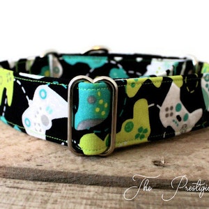 May include: A black and white dog collar with a green and blue video game controller print. The collar has silver metal hardware.