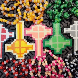 May include: Five colorful beaded cross necklaces with different colored beads. The crosses are made of plastic and are in the shape of a cross. The necklaces are all different lengths and have different colored beads.