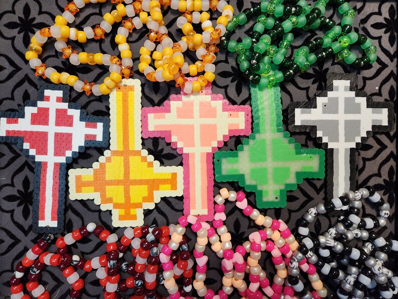 May include: Five colorful beaded cross necklaces with different colored beads. The crosses are made of plastic and are in the shape of a cross. The necklaces are all different lengths and have different colored beads.