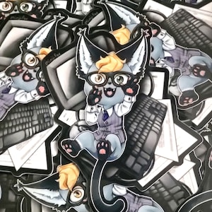 Può includere: Un mucchio di adesivi con un gatto grigio dei cartoni animati che indossa occhiali e un gilet, seduto su una tastiera di computer. Il gatto ha una coda nera e tiene un paio di cuffie. Gli adesivi sono stampati con il testo "MiniFox".