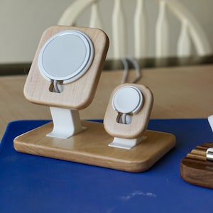 May include: Wooden charging stands for a phone and watch, with white charging pads. A small bust of Abraham Lincoln and a pen rest with pens are also displayed. The items are on a blue surface.