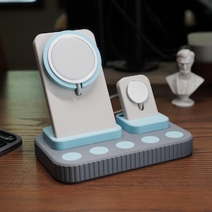 May include: A multi-device charging station in gray, light blue, and white. The station has a stand for a phone and a watch, with a circular charging pad. The base has several circular accents.
