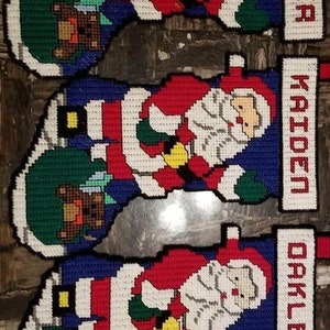 Könnte beinhalten: Drei Weihnachtsstrümpfe mit Weihnachtsmann-Motiven und personalisierten Namen: Hunter, Kaiden und Oakley.