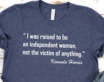 May include: A navy blue t-shirt with a white quote that reads "I was raised to be an independent woman, not the victim of anything." The quote is attributed to Kamala Harris.