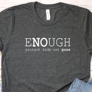 May include: A dark gray t-shirt with the text "ENOUGH protect kids not guns" printed in white.