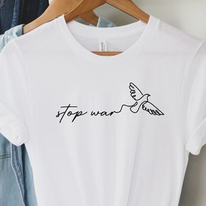 May include: White t-shirt with a black line drawing of a dove and the text "stop war" on the front.