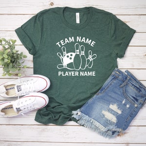May include: A green t-shirt with white text that says "Team Name" and "Player Name". A white bowling ball and pins are in between the text.