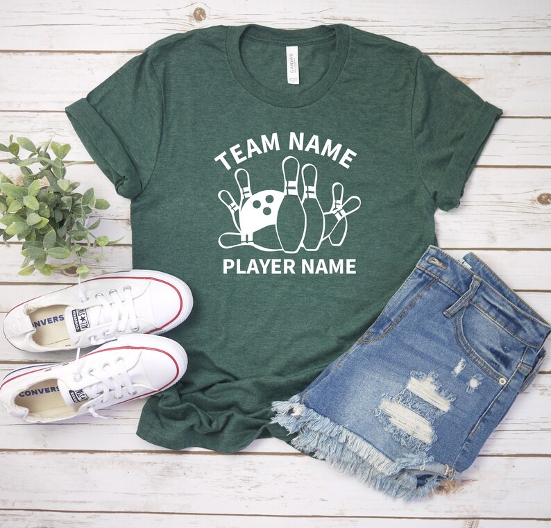 May include: A green t-shirt with white text that says "Team Name" and "Player Name". A white bowling ball and pins are in between the text.