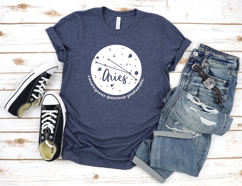Pu&ograve; includere: Una t-shirt blu navy con un grafico circolare bianco che presenta la costellazione dell'Ariete e le parole "Ariete, coraggioso, generoso, passionale".