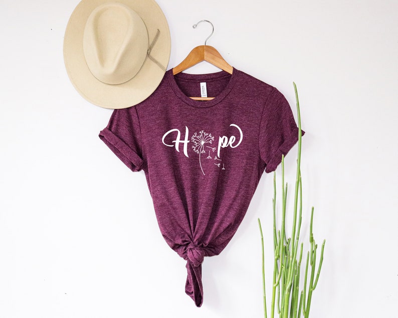 May include: Burgundy t-shirt with a white dandelion graphic and the word "Hope" in a cursive font.