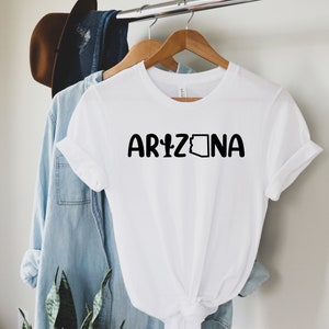 May include: White t-shirt with black text that reads "ARIZONA" and a black outline of the state of Arizona.