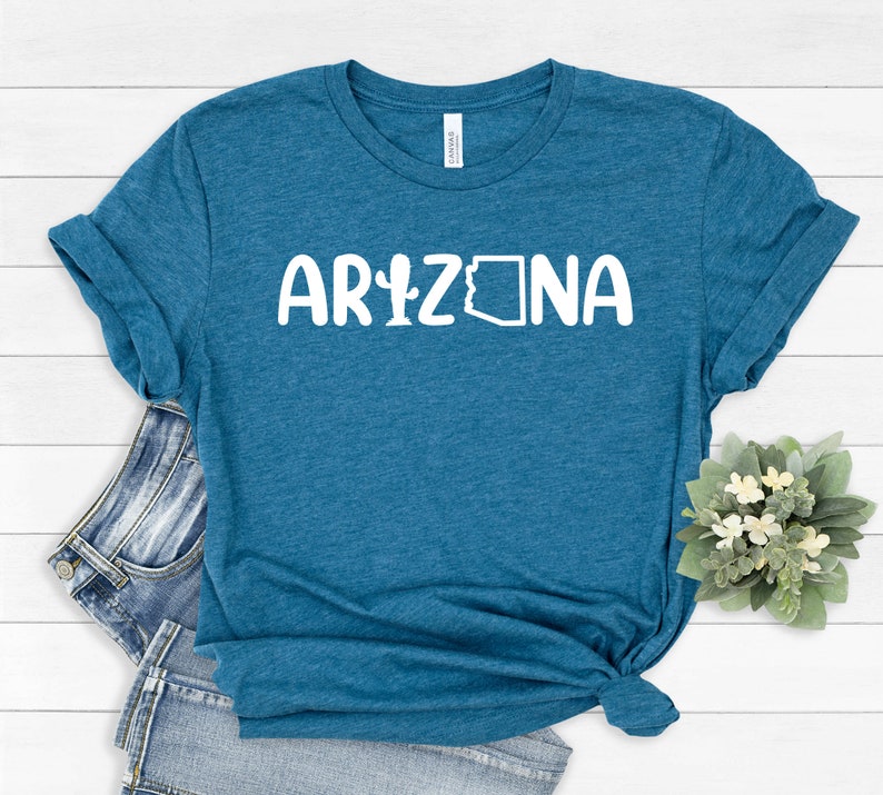 May include: A teal blue t-shirt with the text "ARIZONA" in white, featuring a cactus and the outline of the state of Arizona.