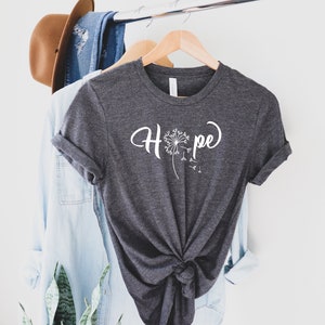 May include: A dark gray t-shirt with a white dandelion graphic and the word "Hope" written in a cursive font.