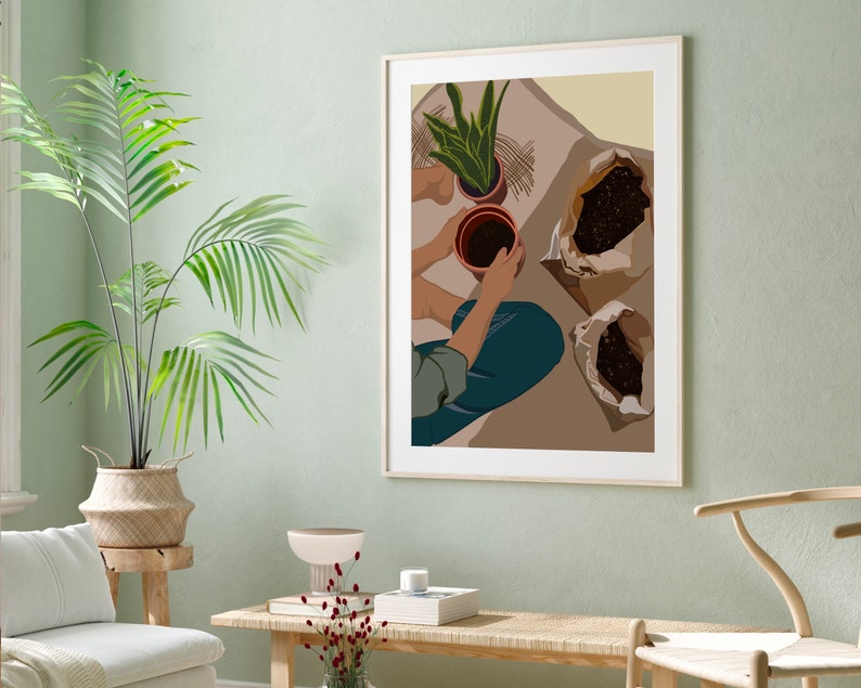 May include: A framed illustration of a person potting plants. The illustration is in a minimalist style with brown, green, and beige colors. The person is wearing blue jeans and a green shirt. There are three brown pots with plants and two bags of soil on the floor.