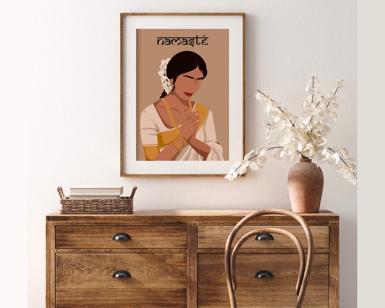 May include: A digital illustration of a woman in a white and gold sari with her hands clasped in a prayer position. The background is a light brown color and the text "namaste" is written in black at the top of the image.