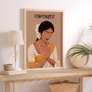 May include: A digital illustration of a woman in a white and gold sari with her hands in a prayer position. The background is a light brown color and the text "namaste" is written in black at the top of the image.