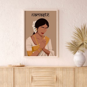May include: A digital illustration of a woman in a white and gold sari with her hands in a prayer position. The background is a light brown color and the text "namaste" is written in black at the top of the image.