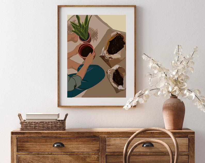 May include: A person is potting plants. They are holding a brown pot with soil in it. There are two bags of soil on the floor. The background is a light beige color.