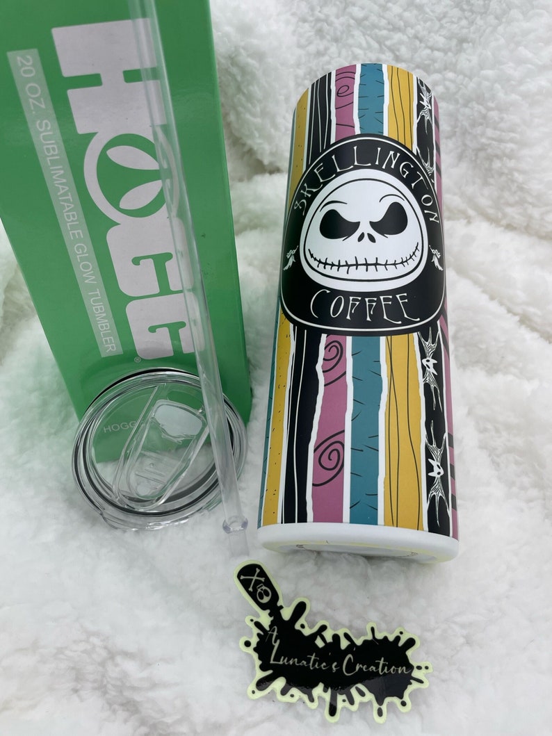 Op de afbeelding: Een 20 oz. sublimineerbare glow-beker met een zwart-wit afbeelding van Jack Skellington uit The Nightmare Before Christmas. De beker heeft een gestreept ontwerp met roze, paarse, blauwe, gele en zwarte strepen. De tekst "Skellington Coffee" is op de beker gedrukt.