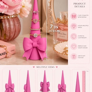May include: A bright pink cone-shaped ring holder featuring a large decorative bow at the base. The holder stands 7 inches tall and is shown displaying four rings. The product details list features including a coquette bow design and lightweight build.