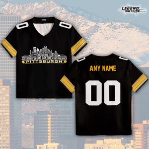 May include: Black jersey with gold and white accents. The front features a Pittsburgh skyline graphic with player names. The back has "ANY NAME" above the number "00". The jersey has a V-neck and striped sleeves.