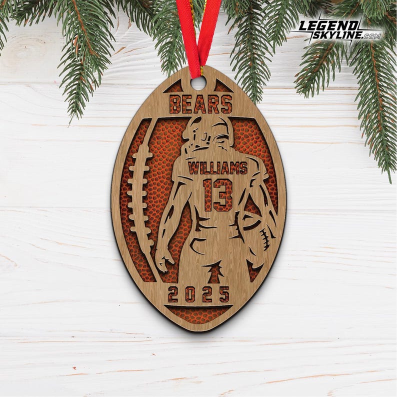 May include: Wooden football-shaped ornament with a football player design. The ornament features the word "BEARS" at the top, the name "WILLIAMS" and the number "13". The year "2025" is at the bottom. A red ribbon is attached for hanging.