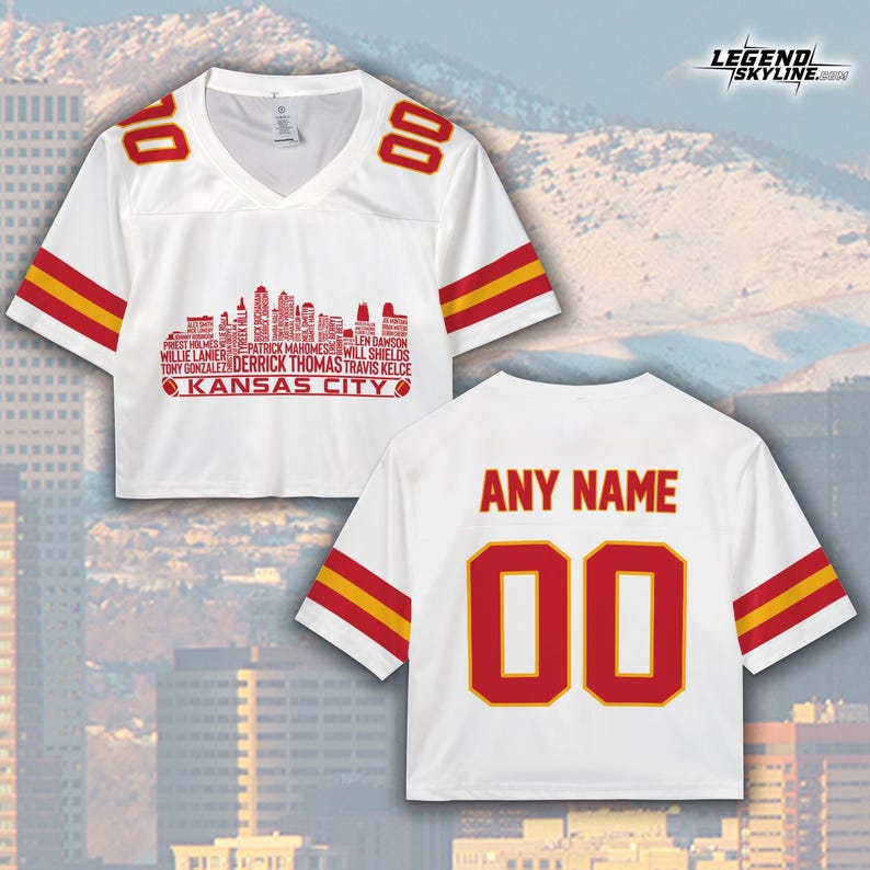 May include: White crop top jersey with red and yellow accents. Features the text "KANSAS CITY" and a skyline graphic. The jersey has the number "00" on the front and back, with "ANY NAME" above the back number.