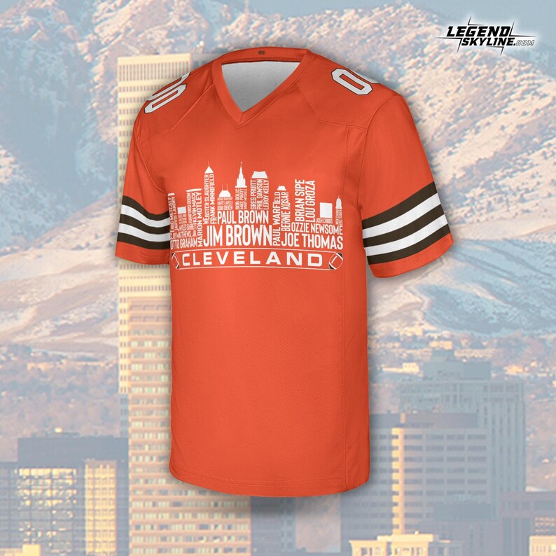 以下が含まれることがあります： オレンジ色のフットボールジャージ。袖には白と茶色のストライプが入っています。肩には数字の「0」があり、選手の名前と「Cleveland」の文字が入った白いスカイラインのグラフィックが特徴です。