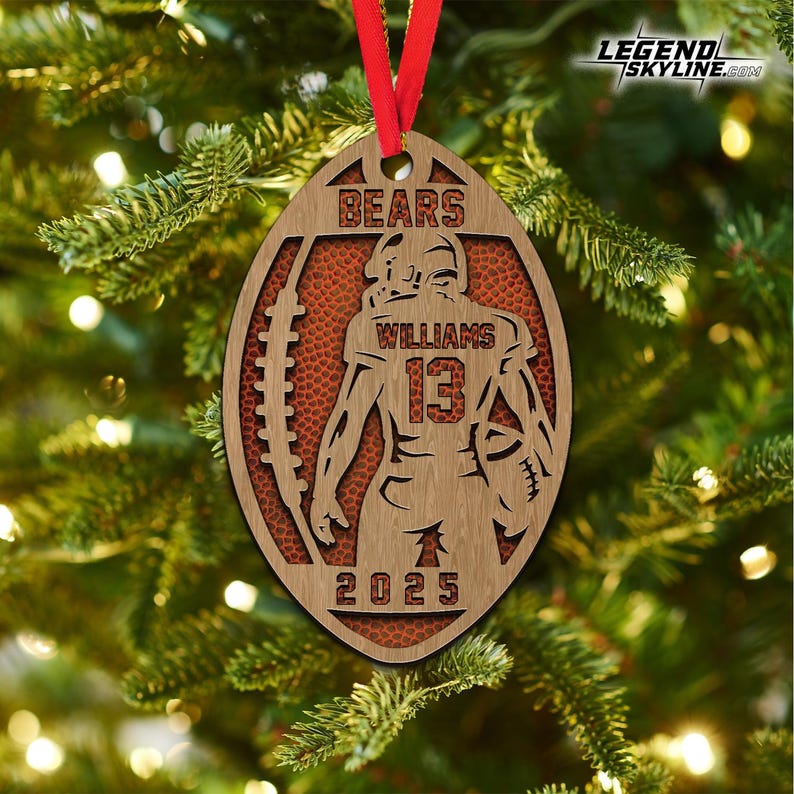 May include: Wooden football-shaped Christmas ornament with a red ribbon. The ornament features a football player silhouette, the name "WILLIAMS" and the number "13". The word "BEARS" is at the top, and "2025" at the bottom.