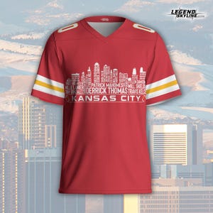 Puede incluir: Una camiseta de f&uacute;tbol roja de los Kansas City Chiefs con rayas blancas y amarillas en las mangas. La camiseta presenta un gr&aacute;fico blanco del horizonte con los nombres de los jugadores y el texto "KANSAS CITY". El logotipo de Legend Skyline est&aacute; en la esquina superior derecha.