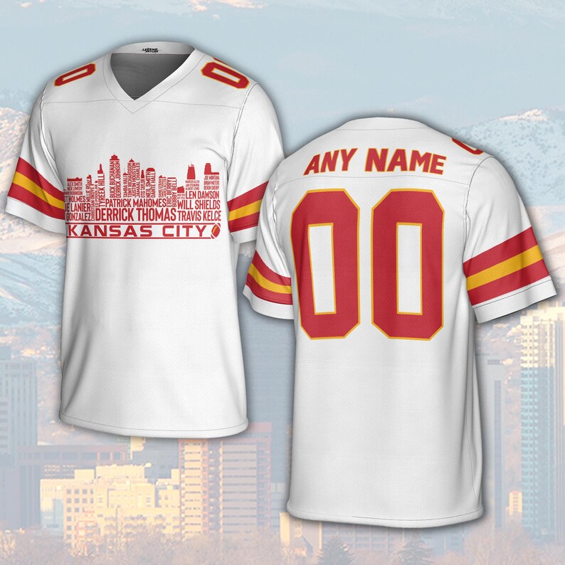 May include: White football jersey with red and yellow accents. The front features a red skyline graphic with player names and "KANSAS CITY". The back displays the number "00" in red with a yellow outline, and the text "ANY NAME" above.