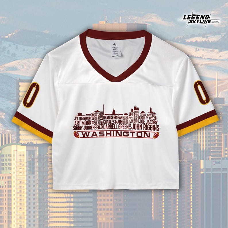 Peut inclure: Maillot court blanc avec un col en V et des bordures de manches bordeaux, portant le chiffre "0" sur les manches. Le devant affiche un graphique de skyline avec des noms de joueurs et le mot "WASHINGTON". Le logo Legend Skyline est en haut &agrave; droite.
