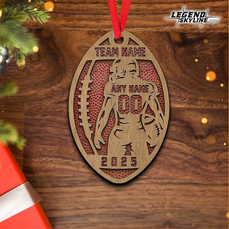 May include: Wooden football-shaped ornament with a red ribbon. The ornament features a football player design with the text "TEAM NAME", "ANY NAME", "00", and "2025". The background is a football texture.