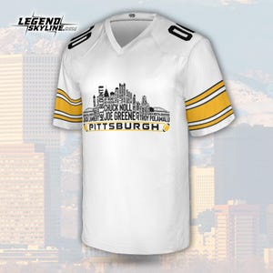 May include: White football jersey with black and gold accents. The jersey features the word "PITTSBURGH" and a skyline design with player names. The sleeves have gold stripes, and the number "10" is on the shoulders.