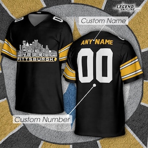 May include: Black and gold football jersey with a V-neck design. The front features a Pittsburgh skyline graphic and player names. The back displays the number "00" and the text "ANY NAME". The sleeves have gold stripes.