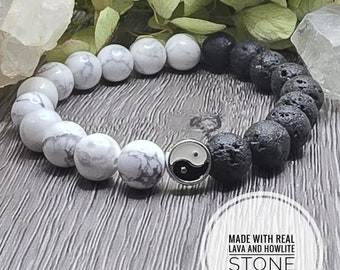 May include: A black lava rock and white howlite stone bracelet with a yin yang charm. The bracelet is made with real lava and howlite stone. "MADE WITH REAL LAVA AND HOWLITE STONE" is written on a white circle.