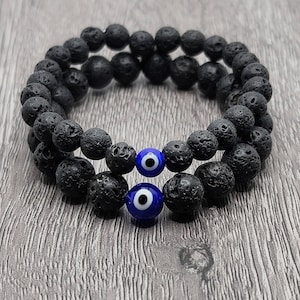 May include: A double-layered black lava rock bracelet with two blue evil eye charms.