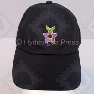 May include: Black baseball cap with a purple star-shaped design, featuring a yellow outline and green leaves. The text "© Hydrangea Press" is printed on the cap. This cap is a stylish accessory.