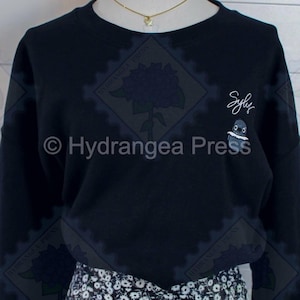 May include: Black long-sleeved sweatshirt with a small embroidered penguin and the word "Sylly" in white thread.