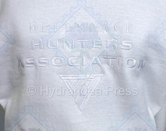 Vit broderad tröja med rund hals, inspirerad av Deepspace Hunter Association-motiv