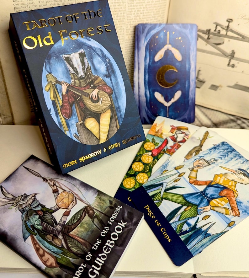 May include: Tarot of the Old Forest deck with a guidebook, featuring a blue and gold card with a badger playing a lute. The card is surrounded by other cards, including the Page of Cups.