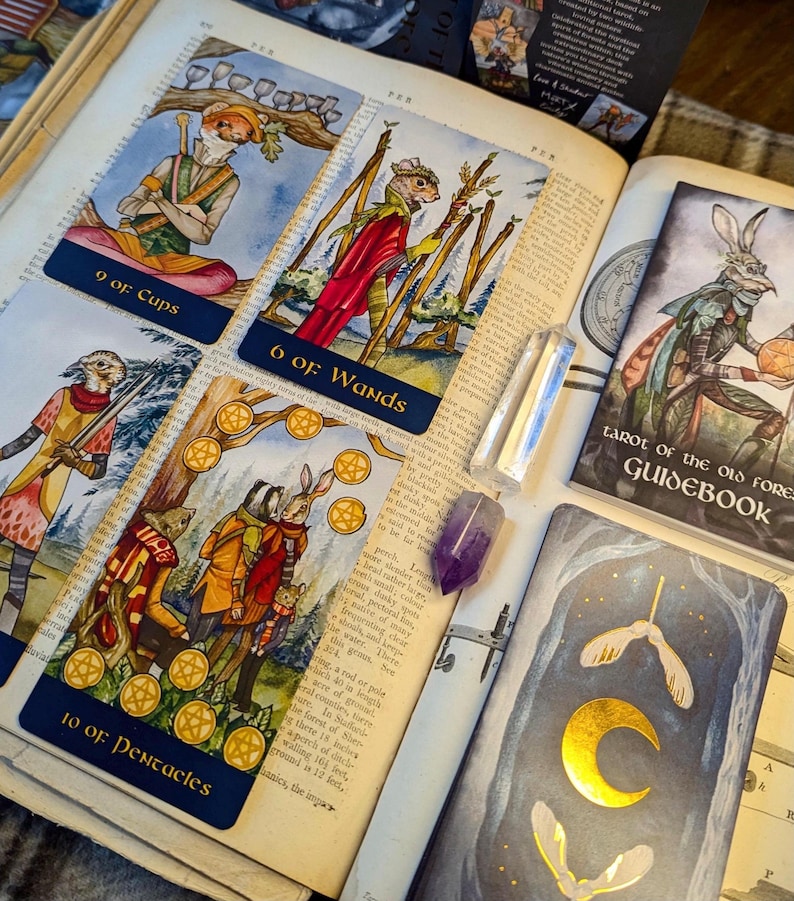 May include: A set of three tarot cards from the "Tarot of the Old Forest" deck. The cards are 9 of Cups, 6 of Wands, and 10 of Pentacles. Each card features a whimsical illustration of woodland creatures in a forest setting. The cards are printed on thick cardstock with a blue border and gold accents.