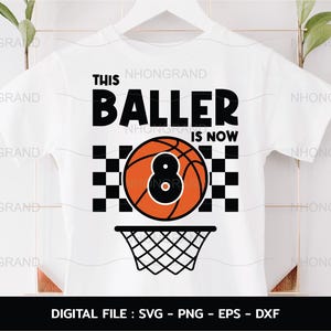 Könnte beinhalten: Weißes T-Shirt mit schwarzem Text, der "This Baller is Now" lautet, und einer Basketballgrafik mit der Nummer 8. Der Basketball befindet sich in einem karierten Muster und hat einen Basketballkorb darunter.